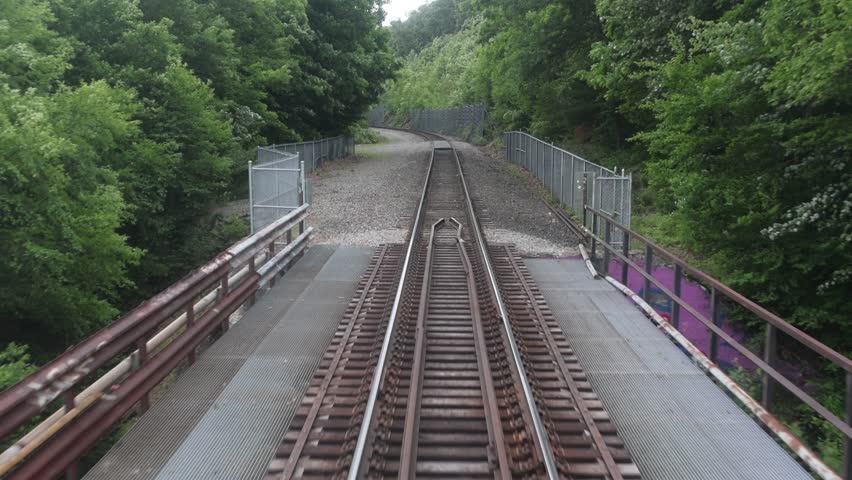 view of moving train tracks from the back of metro car window new york jersey transit north (riding subway travel transportation) gravel rail track bed