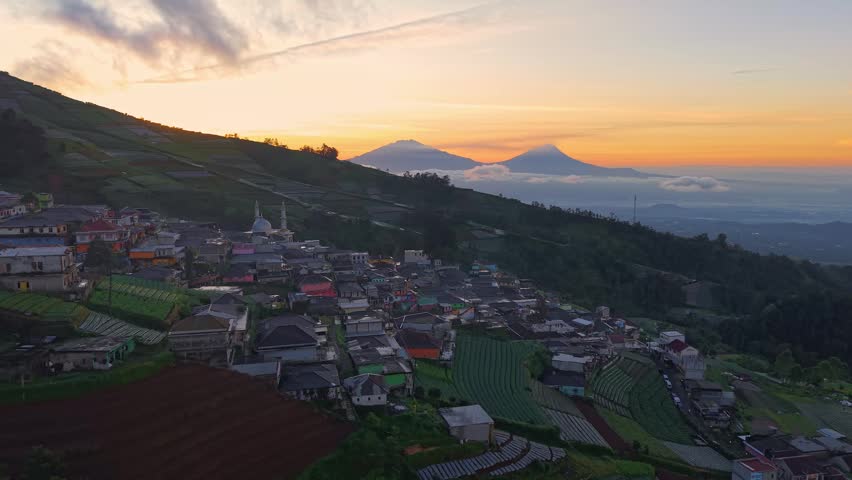 Scenic aerial of hillside village at sunrise, vibrant landscape with terraces and glowing sky. Nepal Van Java, Indonesia.