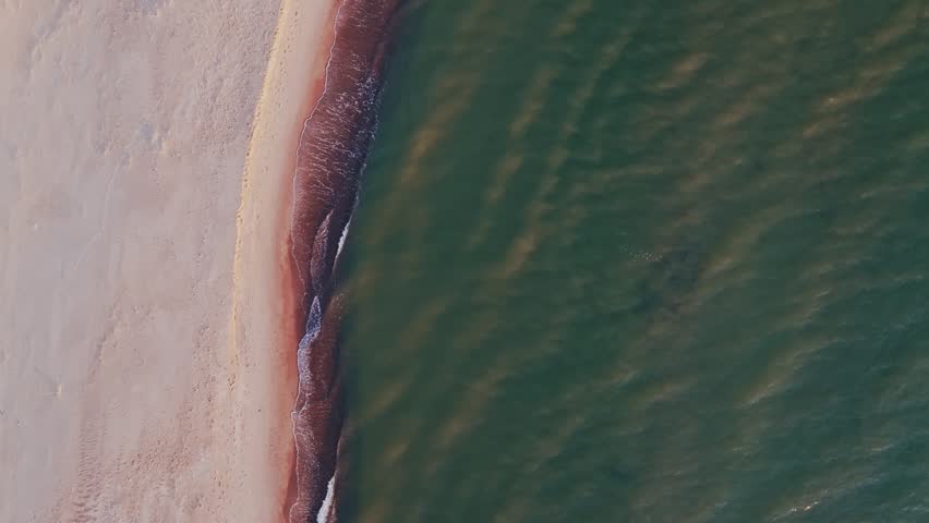 Waves gradually erase the shoreline boundary symbolizing environmental change