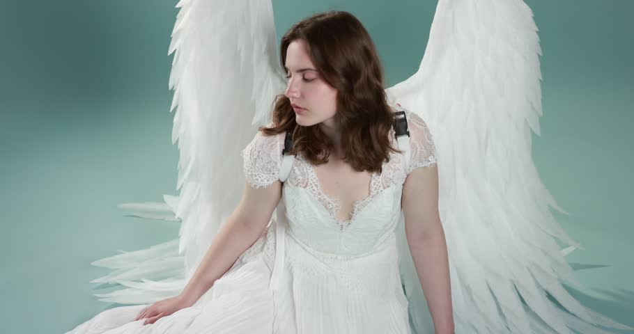 Beautiful girl with angel wings on light blue background, camera moving in