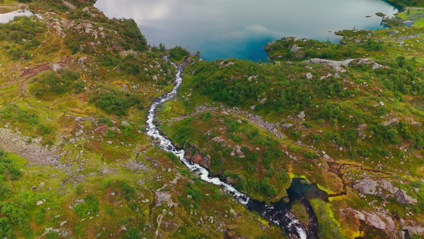 Aerial view of a traditional red Norwegian cabin located on the shore of Buervatnet near Buarbreen Glacier and Odda in western Norway. Scenic mountain landscape and iconic Nordic architecture captur