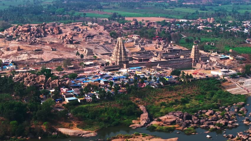 Aerial view of Virupaksha Temple with hampi bazar, Tungabhadra river and crop field lands at hampi, Vijayanagara Empire, karnataka, india. day time, push back shot, drone shot, 4k.
