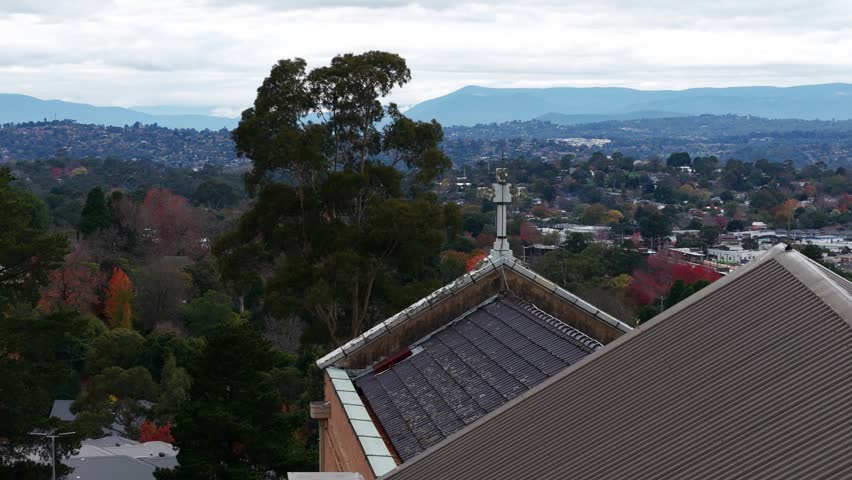 Aerial view of a church roof with a cross overlooking a valley town