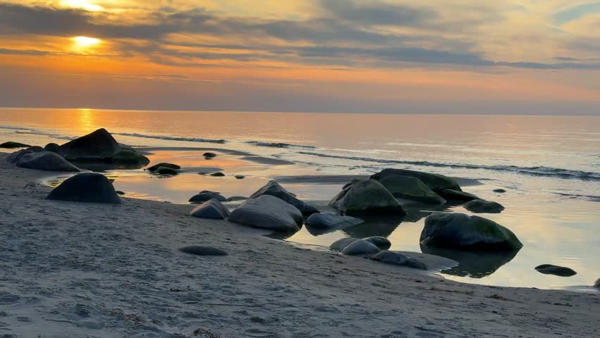Rocky beach coastline on Ruegen island in Germany during sunset over the Baltic Sea. Travel, nature and seaside landscape with calm evening atmosphere.