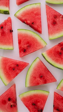 Watermelon slices flatlay vertical white background red juicy scattered pattern fresh summer food photography organic healthy nutrition slow motion texture seeds green rind vibrant product