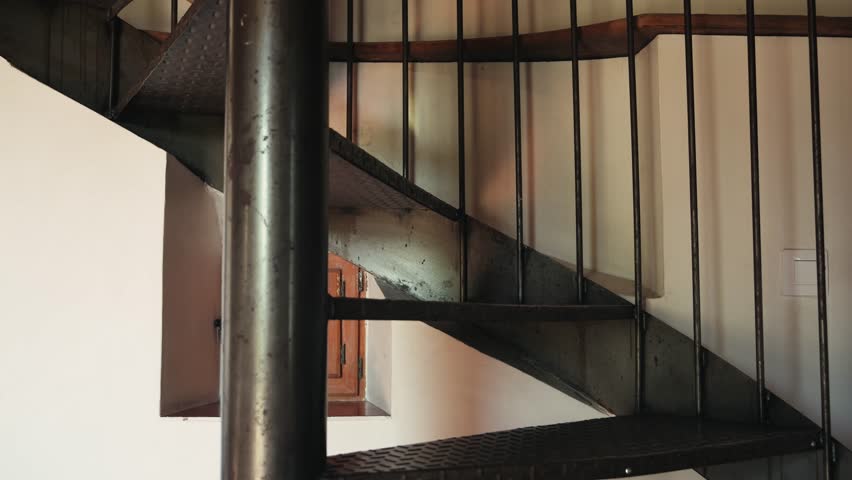 Close-up of feet in flip-flops walking down a metal spiral staircase inside a country house. Everyday home lifestyle concept. High quality 4k footage