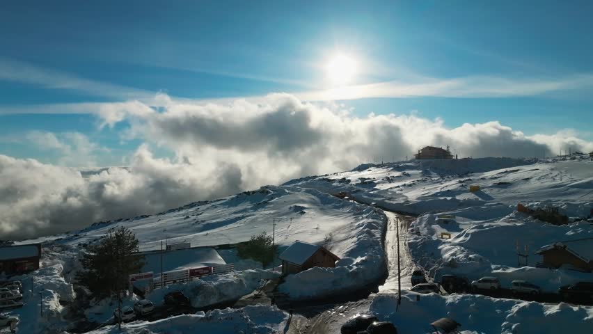 Drone aerial shot over Mount Etna ski resort in winter, revealing snowy slopes and ski lifts, Sicily, Italy, sun and clouds