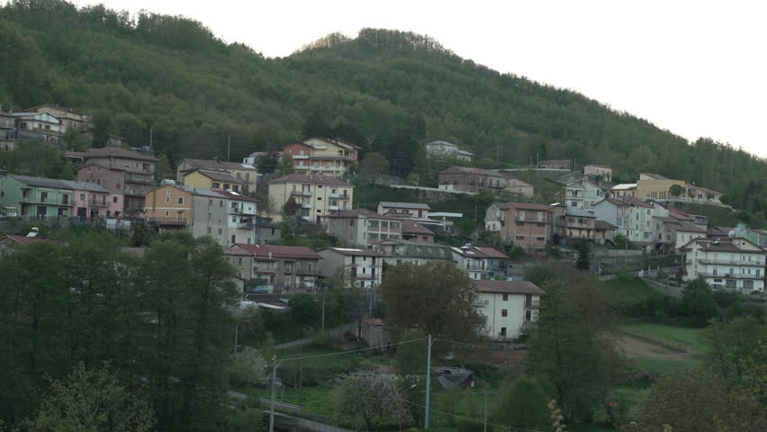 Scenic wide shot of a traditional old village nestled on a green hillside in the rural Apennine mountains of Cosenza province, Calabria region, Southern Italy.