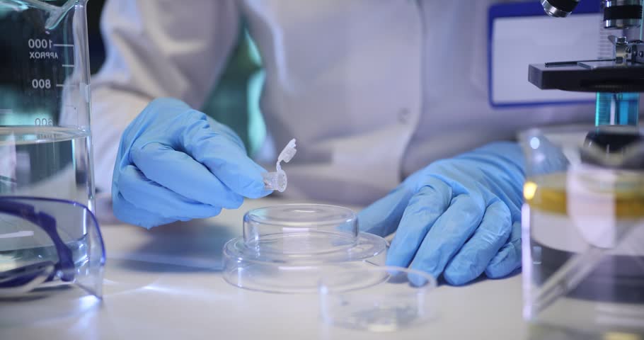 Woman scientist pours metallic liquid onto glass podium in chemical lab. Technician researches silver substance with modern equipment on table