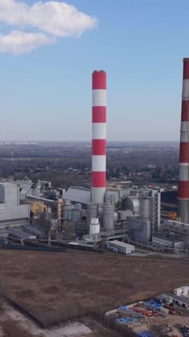 Vertical screen City Fumes Overhead. Factory Smoke Clouds Urban View. Aerial Shot Of Industrial Emissions Over City. Elevated Perspective Showcasing Pollution From Factories In Cityscape
