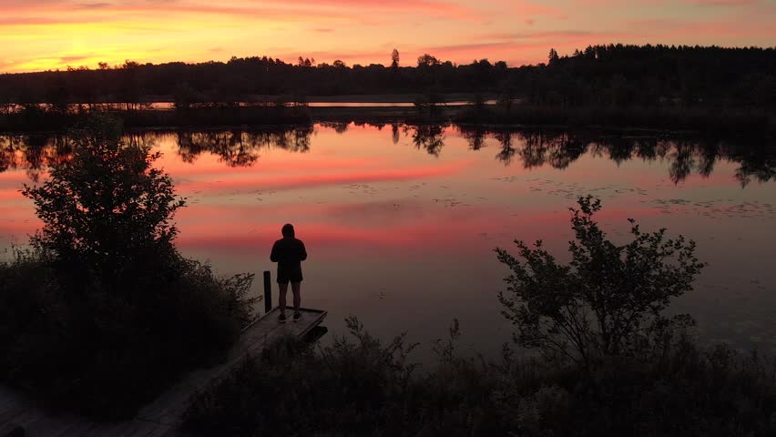 Beautiful view of a man standing next to the lake and waiting sunrise