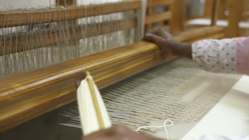 Hands operate traditional wooden weaving loom. Perfect for documentary or educational film.