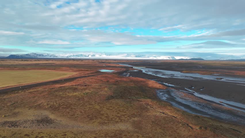 Expansive Icelandic landscape with winding river and distant snowy