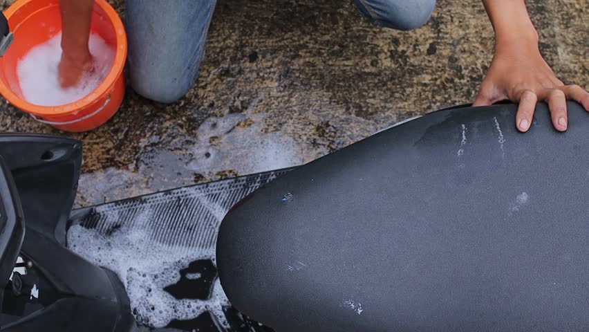 Close up of motorcycle owner clean dirty motorcycle with soap outdoors