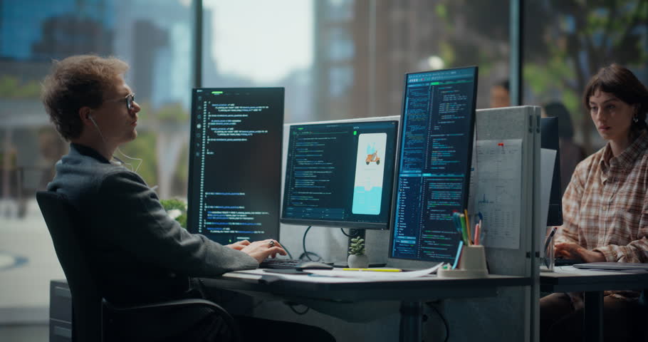Young Male Programmer Typing and Coding in Bright Office, Using Multiple Displays to Test Mobile App Ui, Debug Backend Script, Automation Flow, With Light-skinned Young Female Designer. Working Using Computer