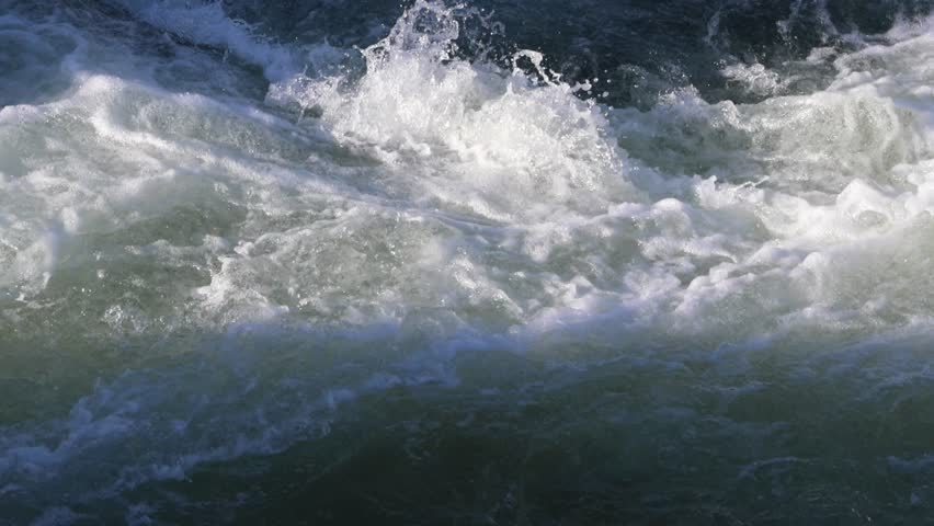 Turbulent river water flowing creating powerful rapids