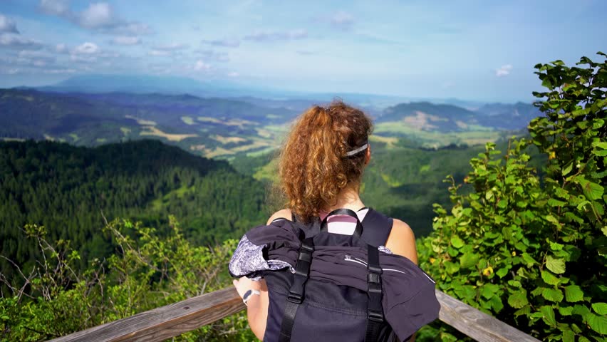 A young hiker admiring the stunning view of hills mountains and forests from a viewpoint on the trail