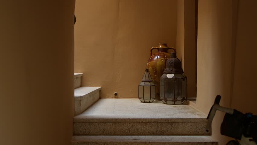 Architectural detail featuring decorative lanterns, ceramic vessels and warm limestone interiors in courtyard within a traditional building