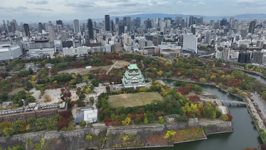 Aerial view of Osaka Castle flying over and revealing the Osaka skyline.
