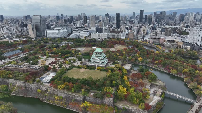 Aerial view of Osaka Castle flying over and revealing the Osaka skyline.