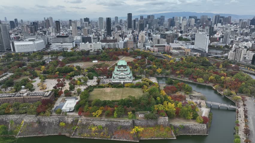 Aerial view of Osaka Castle flying over and revealing the Osaka skyline.