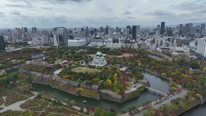 Aerial view of Osaka Castle flying over and revealing the Osaka skyline.