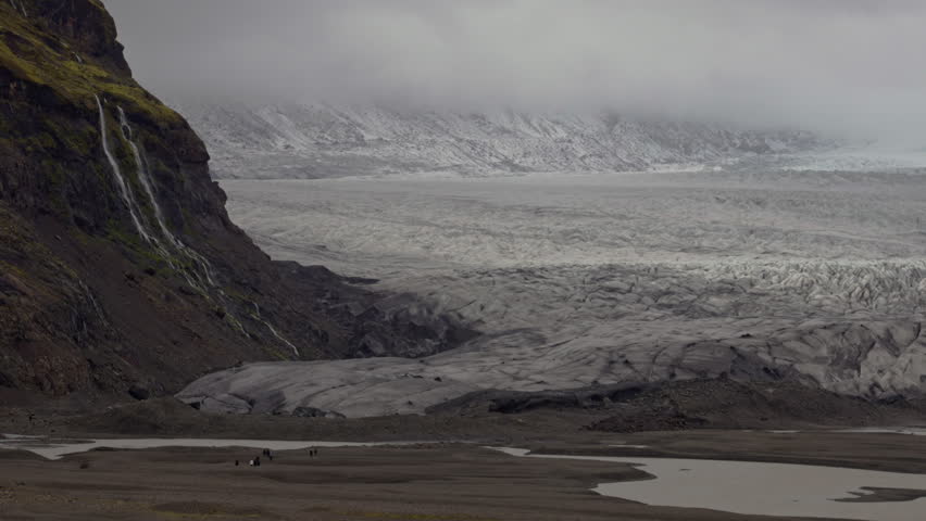 People walking along Jokulsarlon glacier with mountains in background