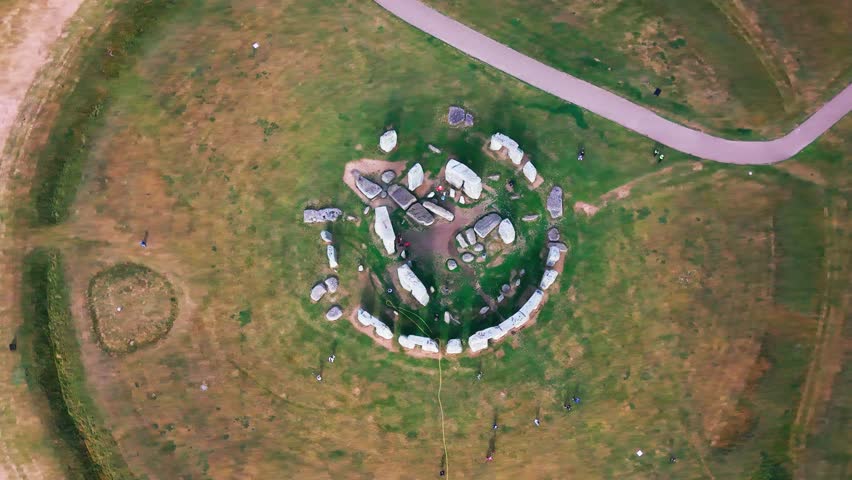 Aerial footage looking down over Stonehenge in Wiltshire, England, showing the prehistoric stone circle, standing stones, visitor paths and surrounding grassland.