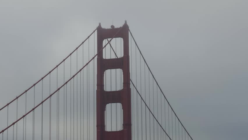 Minimalist close-up shot of the top of the Golden Gate Bridge suspension tower enveloped in dense fog.