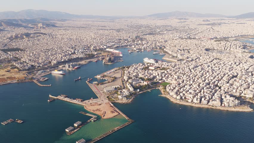 Beautiful aerial flight over the port of piraeus, showing the dense urban landscape of athens, greece, with ferries and ships in the saronic gulf under a clear sunny sky