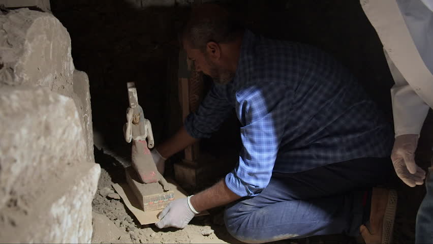 Archaeologists carefully remove a precious ancient Egyptian artifact from an archaeological site