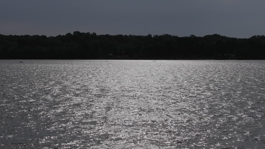 Late afternoon sunlight reflects across the surface of High Rock Lake in North Carolina during the summer season, creating shimmering patterns on the water.