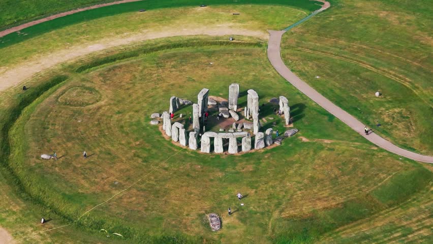 Aerial footage of Stonehenge in Wiltshire, England, showing the prehistoric stone circle, surrounding grassland, visitor paths and open Salisbury Plain landscape.
