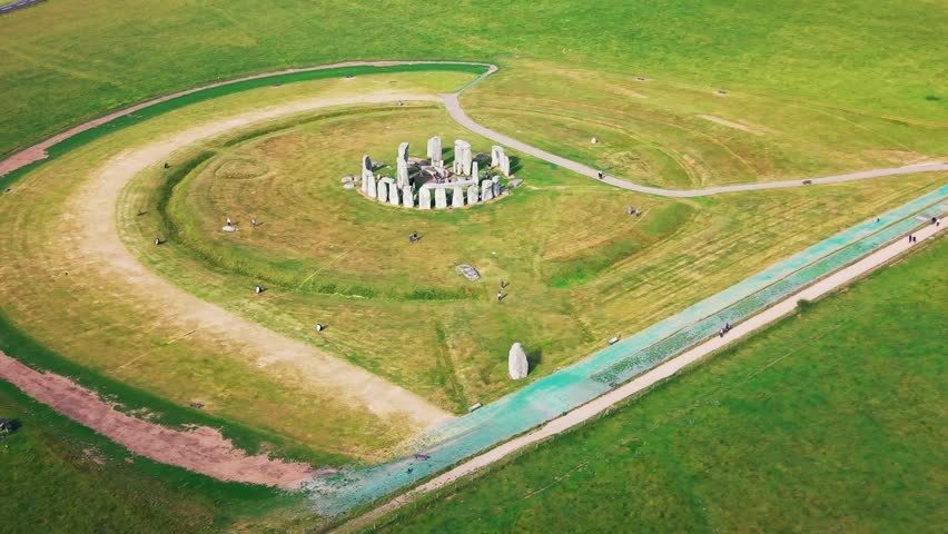 Aerial footage of Stonehenge in Wiltshire, England, showing the ancient stone circle, surrounding grassland, visitor paths and open Salisbury Plain landscape.