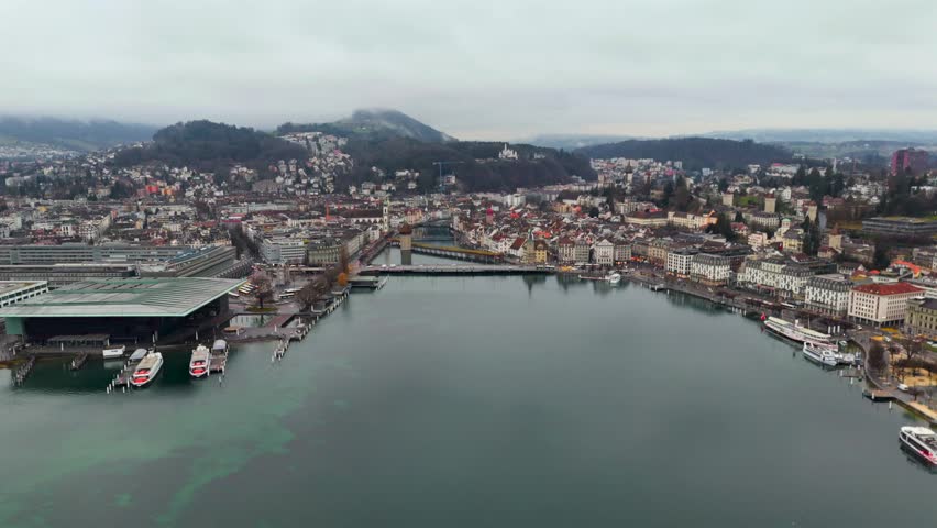 Aerial drone view of Lucerne, Switzerland, showcasing the historic Seebruecke bridge over the Reuss River. Misty autumn landscape, city center, and Alps panorama. Scenic, cinematic, and atmospheric