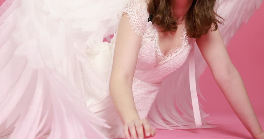 Beautiful girl with angel wings on pink background, camera moving up