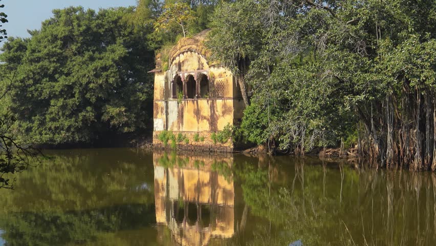 Historical stone building reflected in serene pond forest.