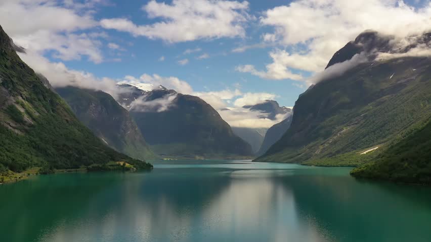 Aerial panoramic view of emerald lake with majestic mountains.