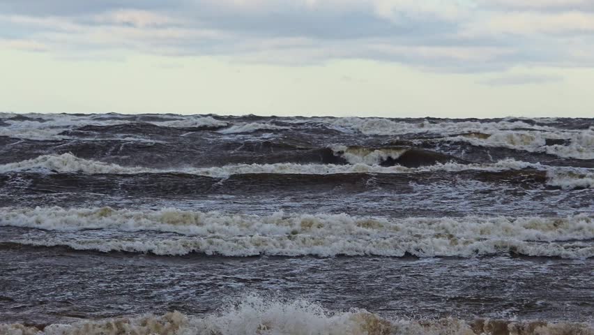 Powerful storm waves rolling across a dark sea under an overcast sky with white foam, rough water and dramatic coastal weather.