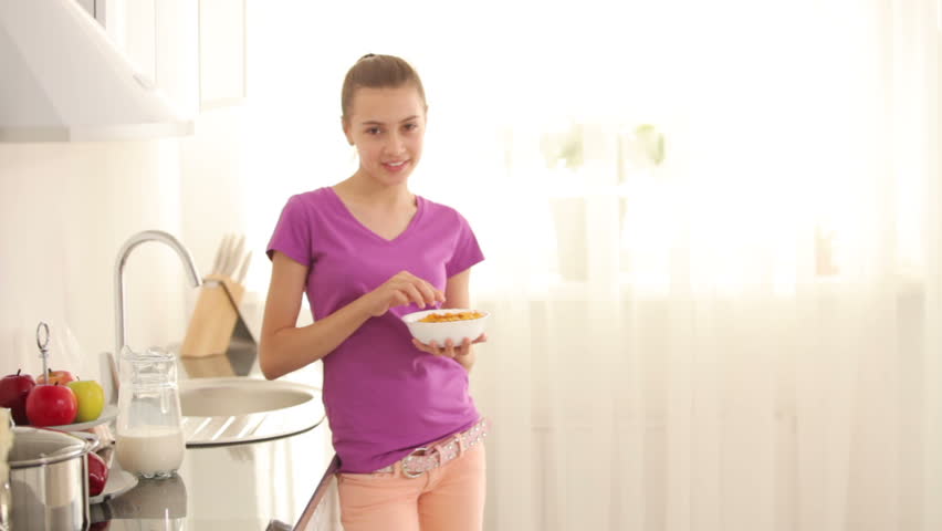 Teenager standing in kitchen and eating cornflakes
