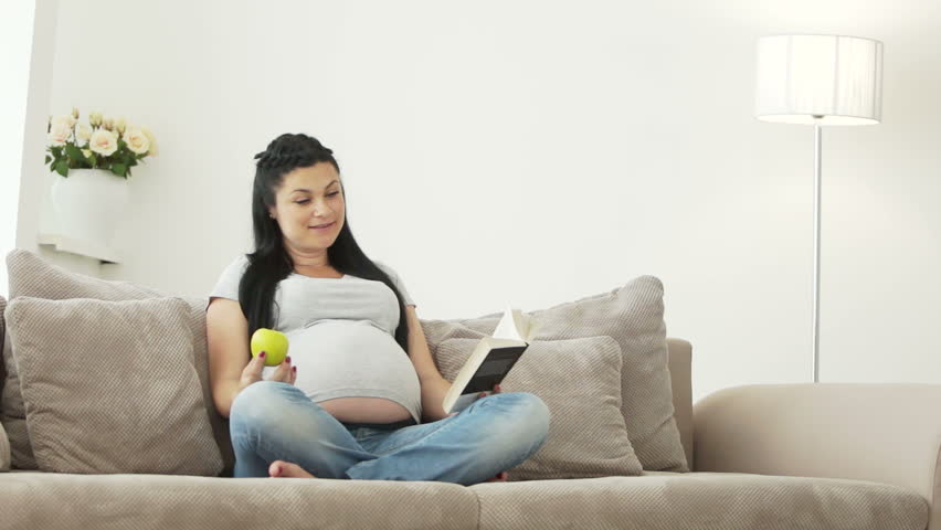 Pregnant woman sitting on a couch with her daughters
