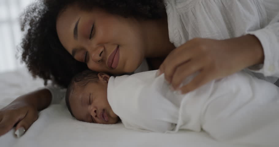 Close up portrait of beautiful young African American mother holding sleep newborn baby in hospital. Healthcare medical love black afro woman lifestyle mother