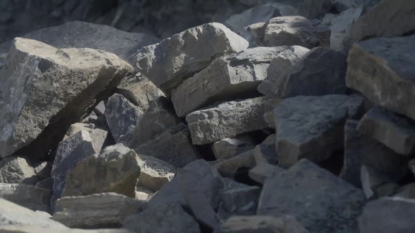 Close-up of large quarried stone blocks stacked in a rock pile. Rough-cut boulders and fractured material showcase extracted aggregate and raw construction resources from a quarry site.