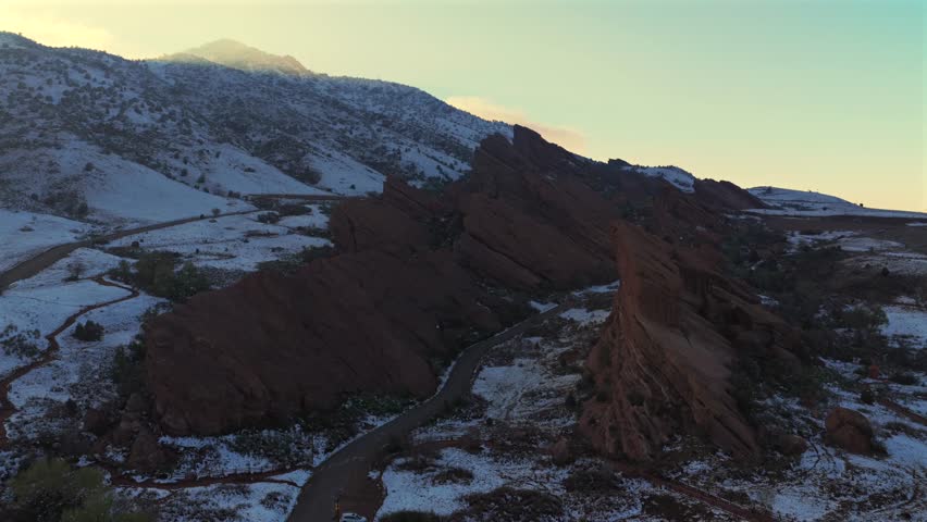 Trading Post Trail road winter on the Rocks sunset Winter Spring fresh snow on Red sandstone Morrison Colorado aerial drone Red Rocks Park and Amphitheater concert event venue landmark forward motion