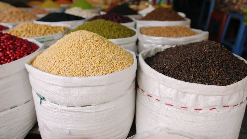 Colorful assortment of beans, grains, and spices for sale at a traditional street market in vietnam.