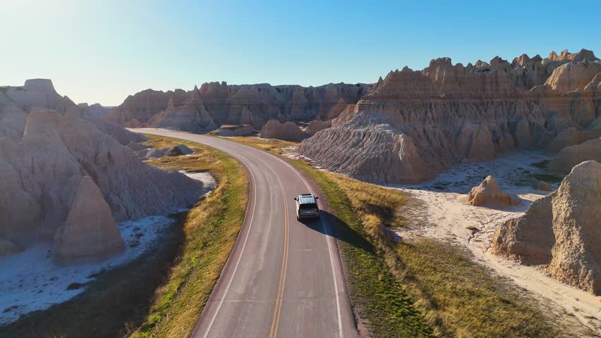 Cinematic Drone View of Dramatic Geological Landscapes, Deep Canyons, and Layered Cliffs in Badlands National Park, America. Car trip around USA