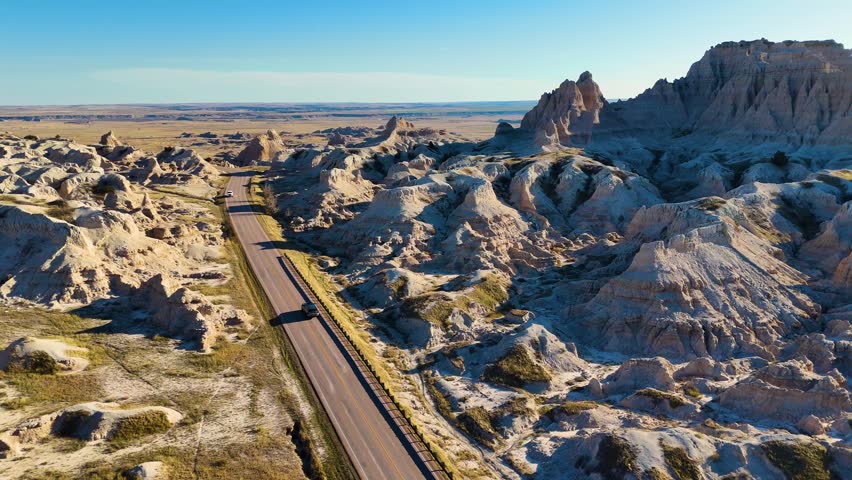Cinematic Drone View of Dramatic Geological Landscapes, Deep Canyons, and Layered Cliffs in Badlands National Park, America. Car trip around USA