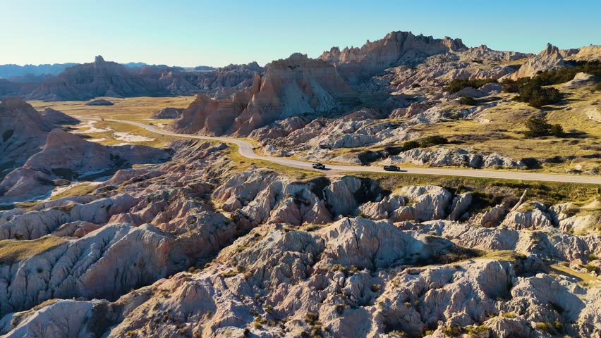 Cinematic Drone View of Dramatic Geological Landscapes, Deep Canyons, and Layered Cliffs in Badlands National Park, America. Car trip around USA