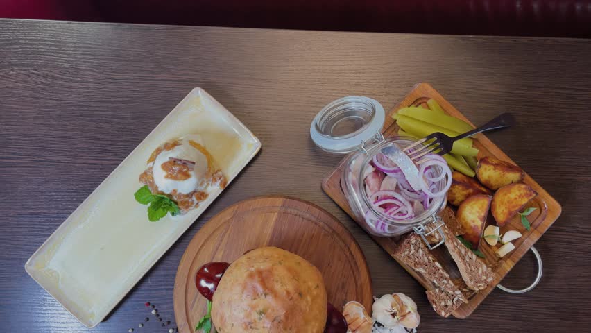 A set of food consisting of herring with onions and appetizers, cast iron with meat and a dough lid and dessert
