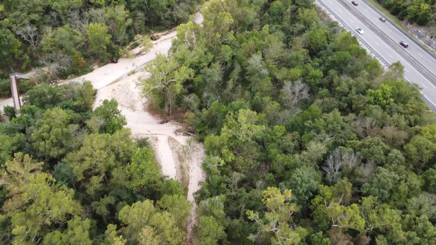 Aerial drone footage capturing a major highway crossing over a winding creek within the forests surrounding Busiek State Forest and Wildlife Area in southwest Missouri.